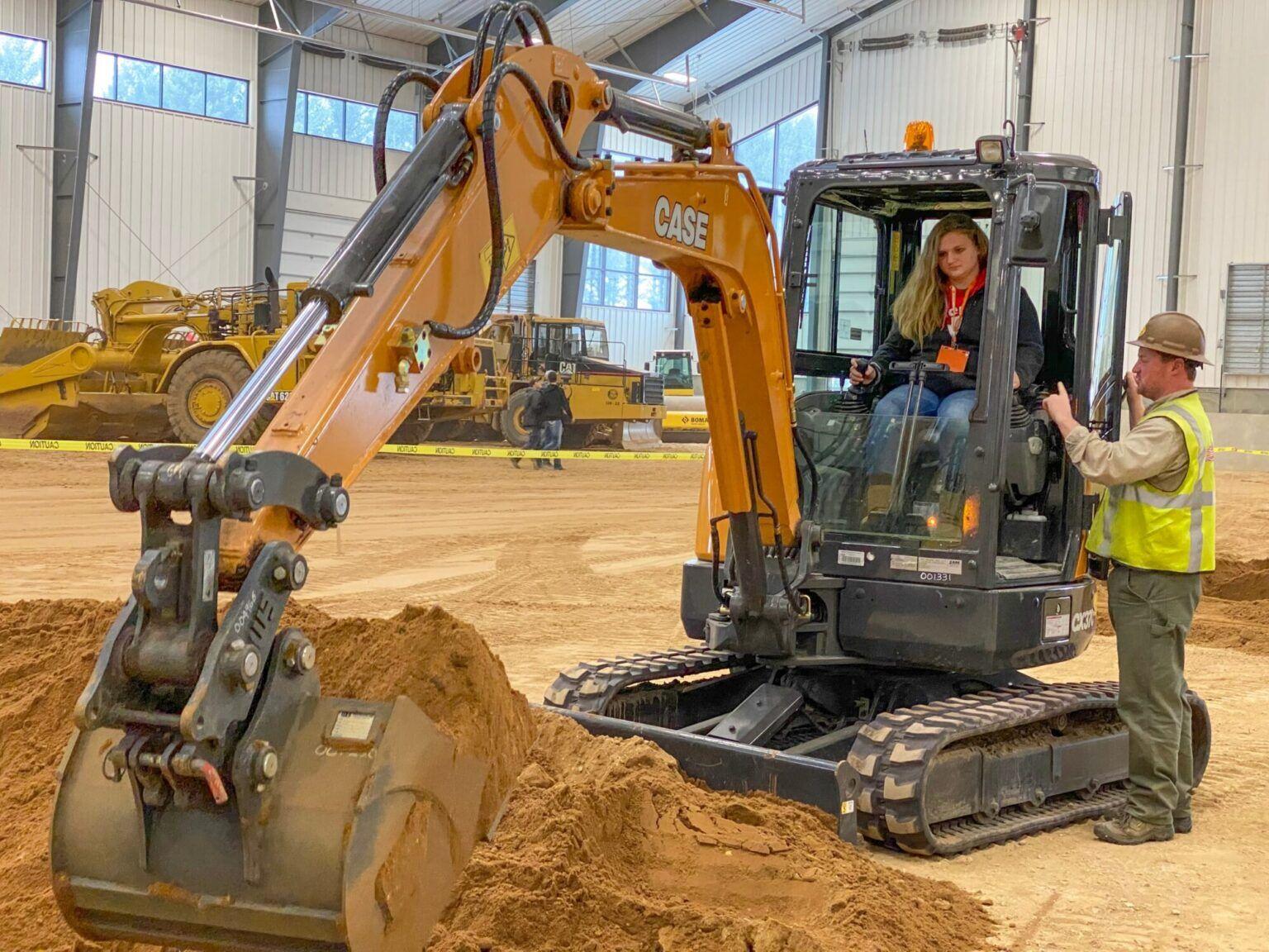 Two people in a yellow heavy machinery moving earth